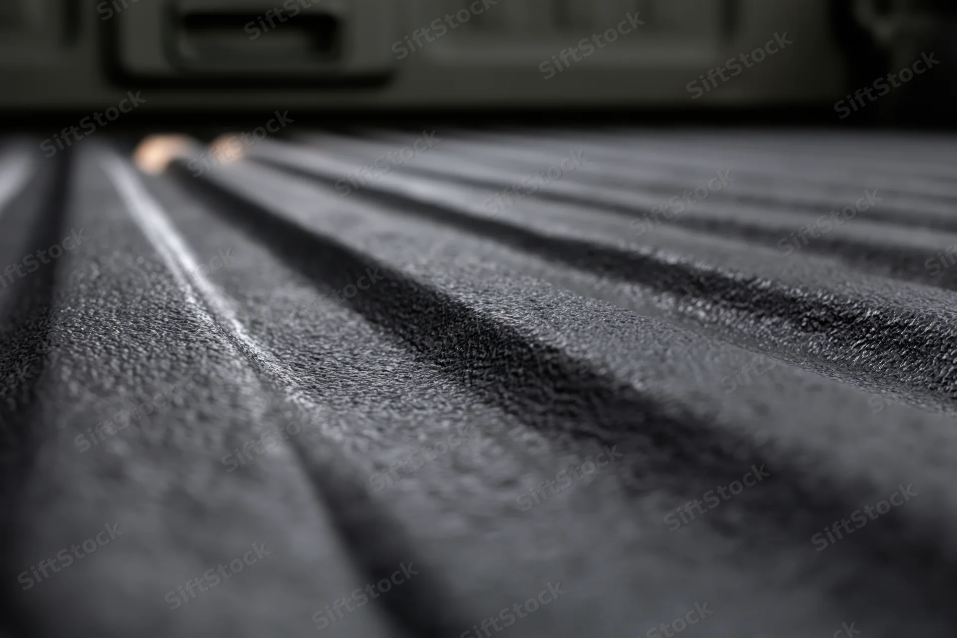 Closeup of textured black rubber liner in pickup truck bed viewed from low angle