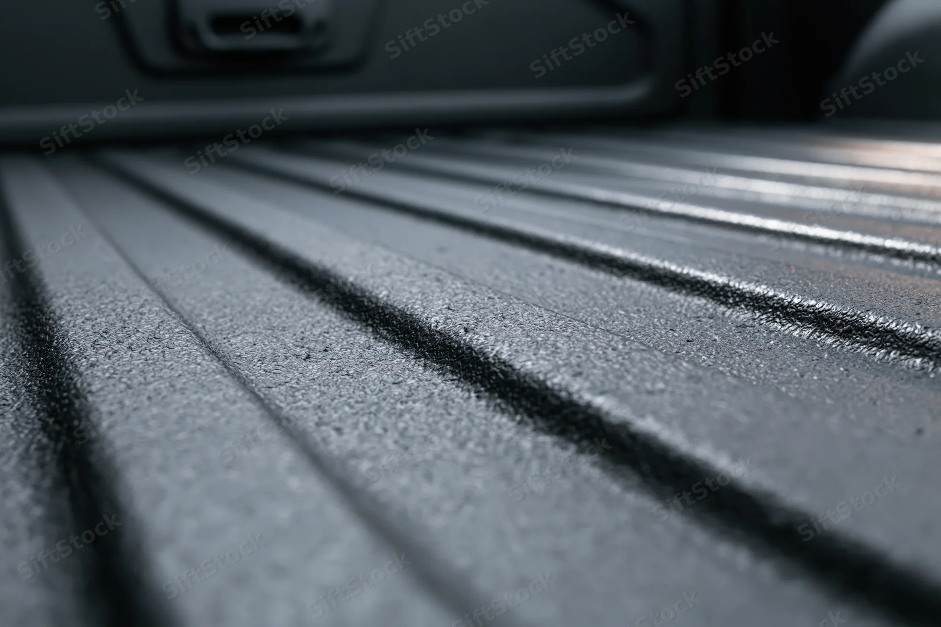 Closeup of ribbed black liner in empty pickup truck bed viewed from low angle