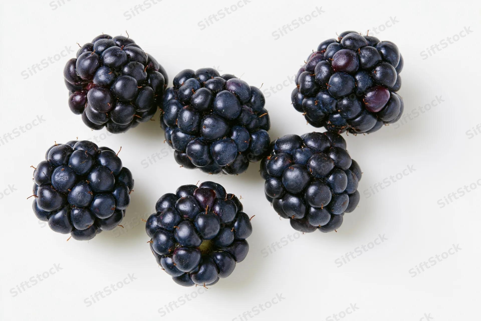 Ripe blackberries scattered on a white surface