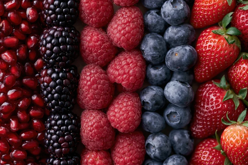 Five varieties of fresh berries arranged in vertical strips forming a colorful pattern