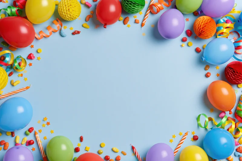Colorful birthday party decorations arranged in a frame border on pale blue background with copyspace
