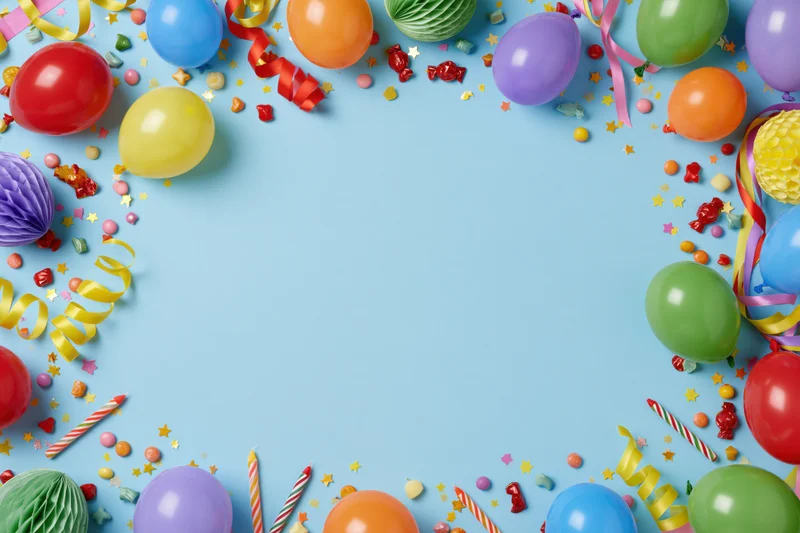 Colorful birthday party decorations arranged in a border frame on pale blue background with copyspace