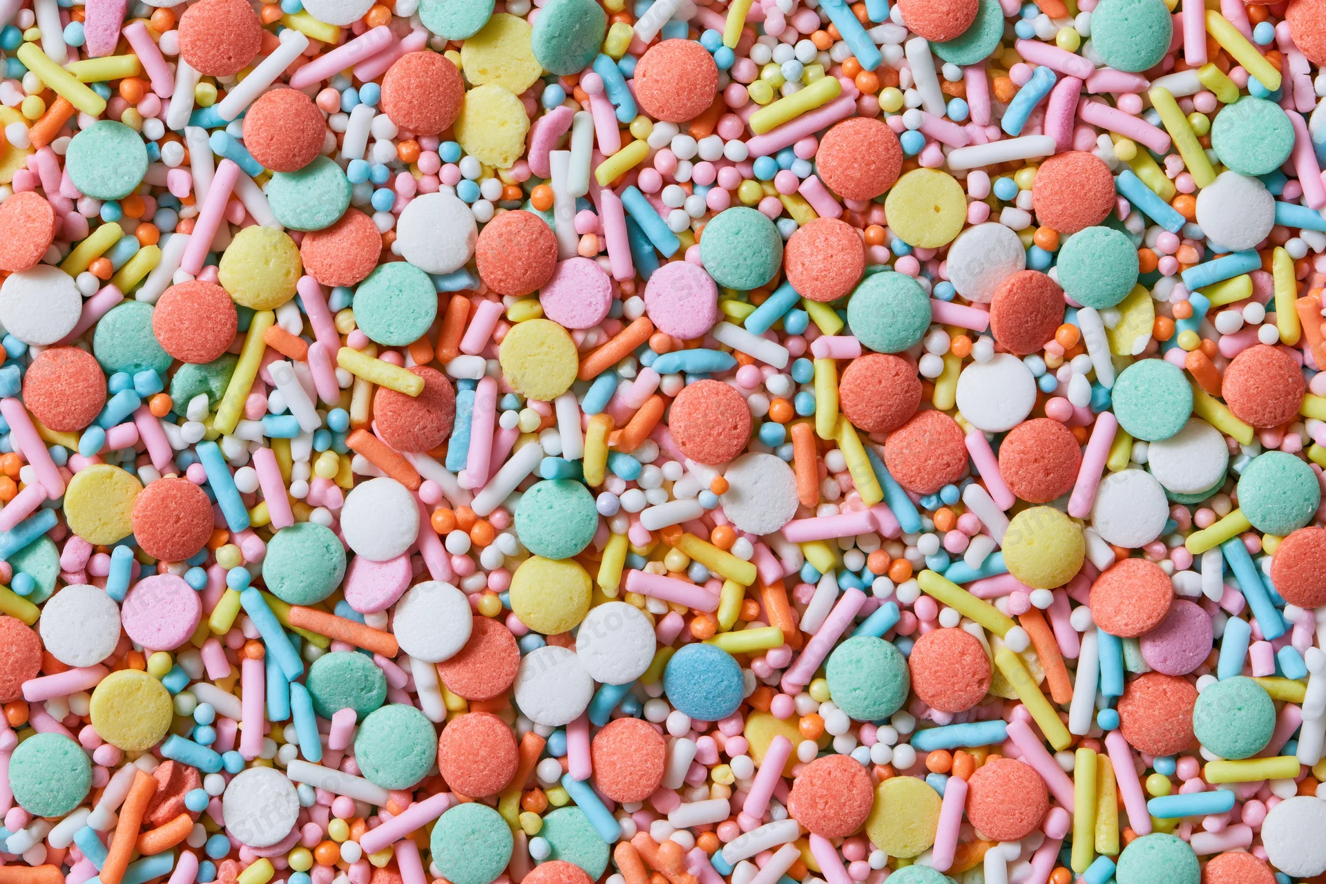 Colorful candy sprinkles scattered densely across a flat surface