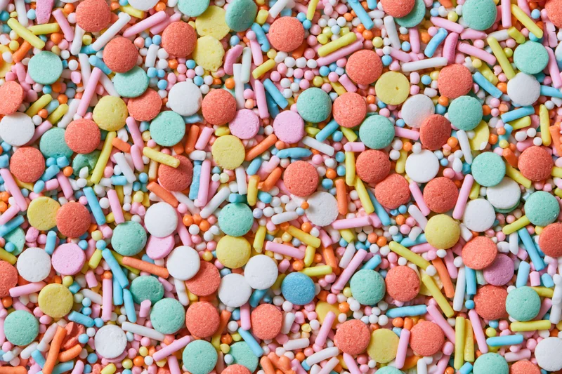 Colorful candy sprinkles scattered densely across a flat surface