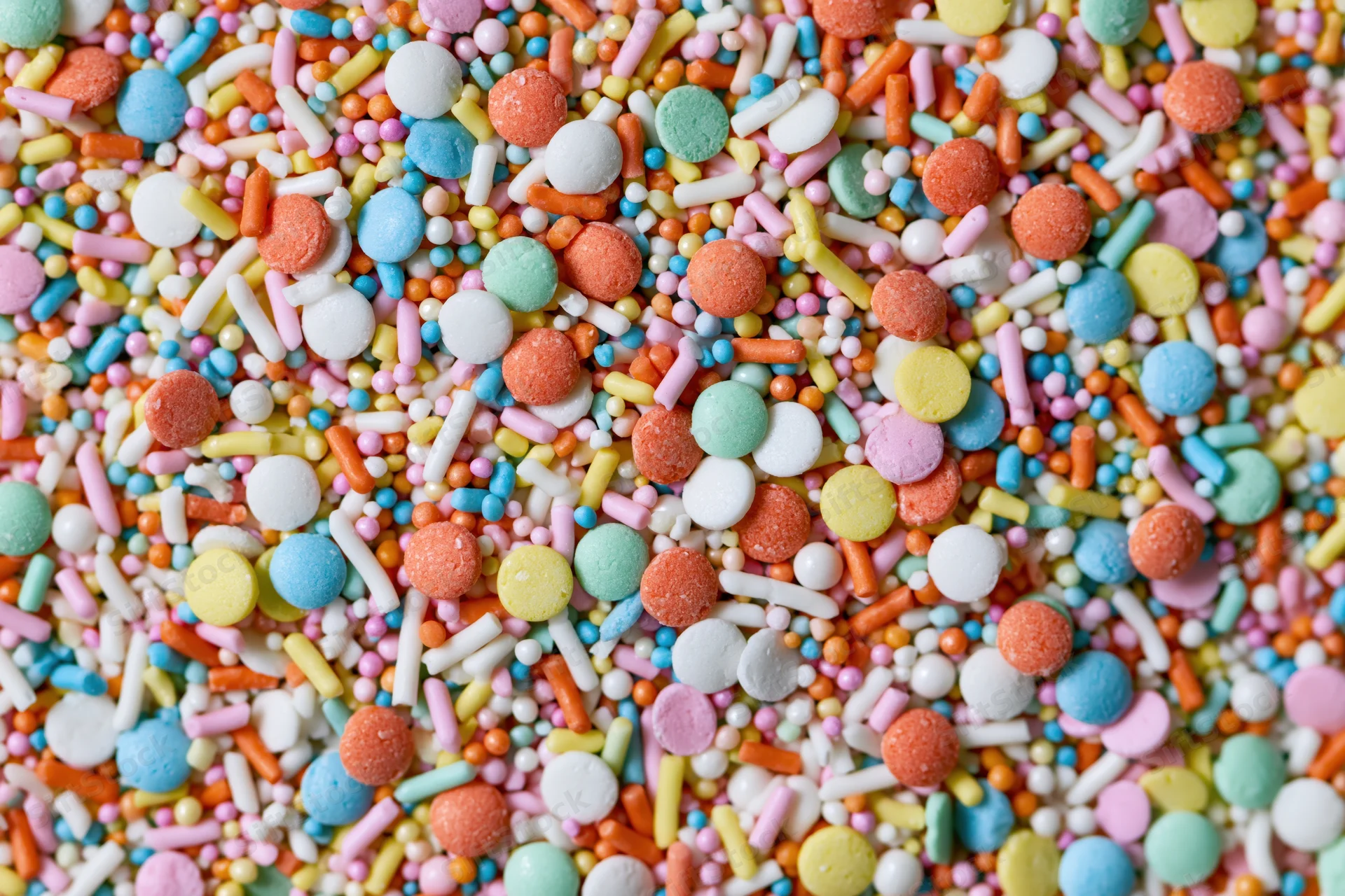 Close-up of colorful candy sprinkles scattered across the frame in a flat lay arrangement