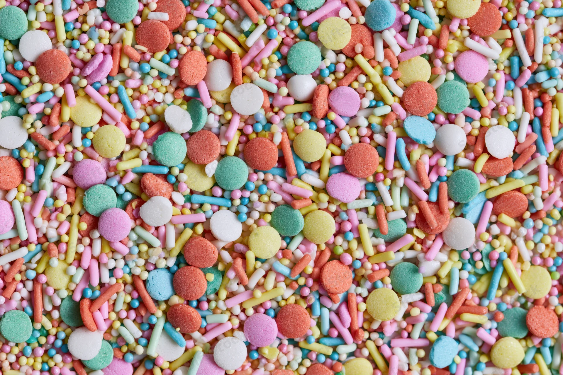 Colorful candy sprinkles scattered in a flat lay close-up filling the frame