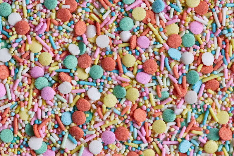 Colorful candy sprinkles scattered in a flat lay close-up filling the frame
