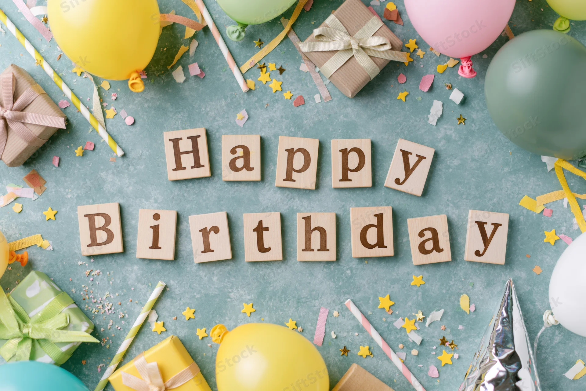 Wooden blocks spelling happy birthday surrounded by party supplies on a flat surface