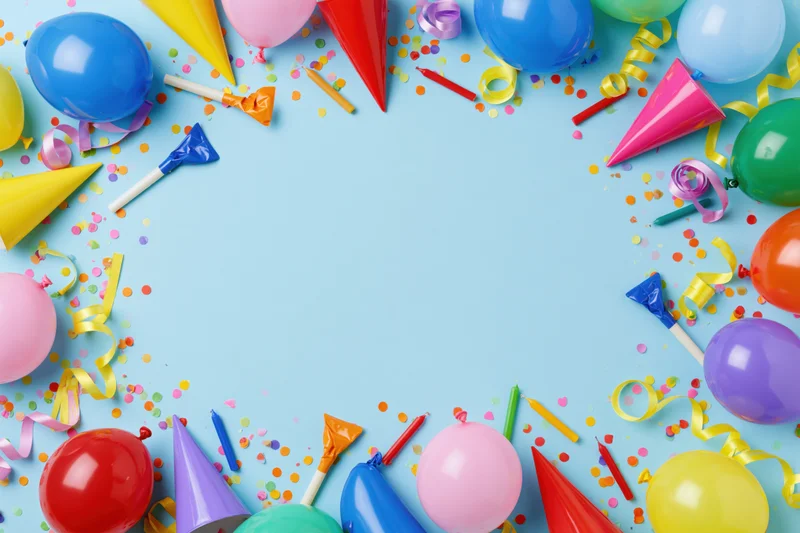 Colorful birthday party supplies arranged in a circle on blue background with copyspace in center