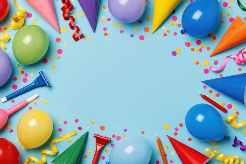 Colorful birthday party supplies arranged in a circle on blue background with copyspace in center