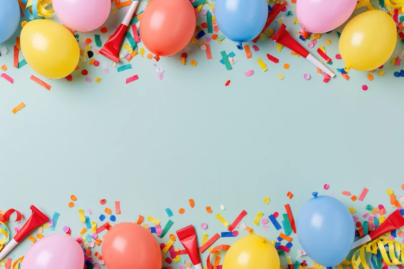 Colorful party supplies arranged in border frame on pastel background with copyspace