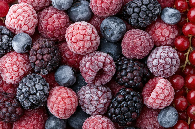 Mixed frozen berries including raspberries, blackberries, blueberries and redcurrants in a flat lay arrangement