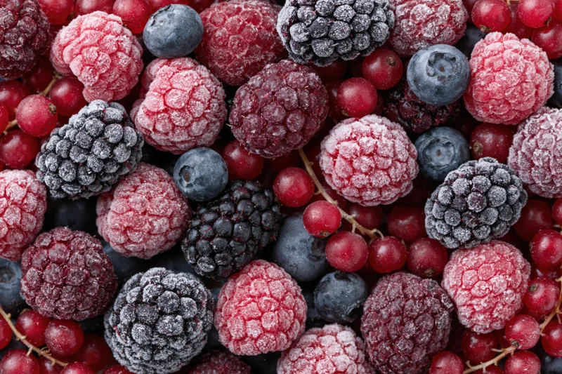 Closeup of mixed frozen berries including raspberries, blackberries, blueberries and redcurrants arranged in a flat lay