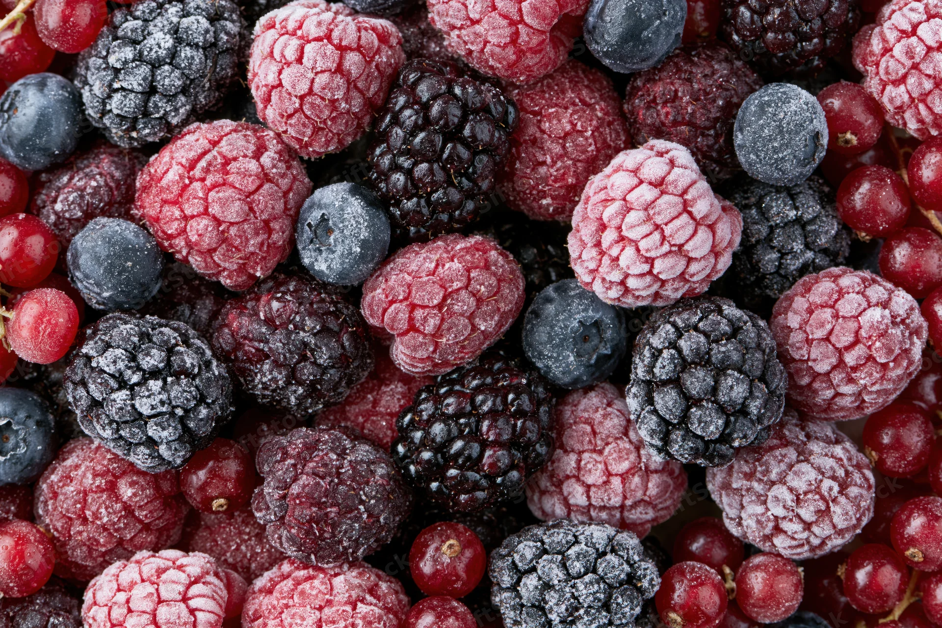 Closeup of mixed frozen berries including raspberries, blackberries and blueberries arranged in a flat lay
