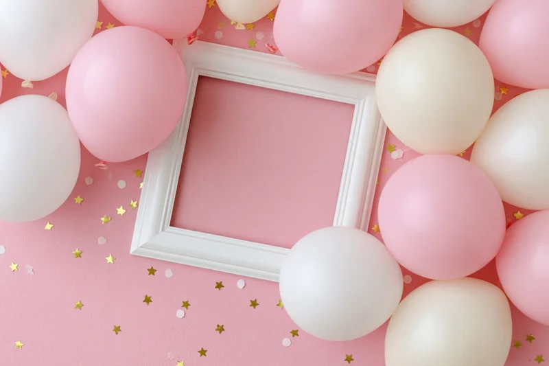 Flat lay of pink and white balloons around a white frame