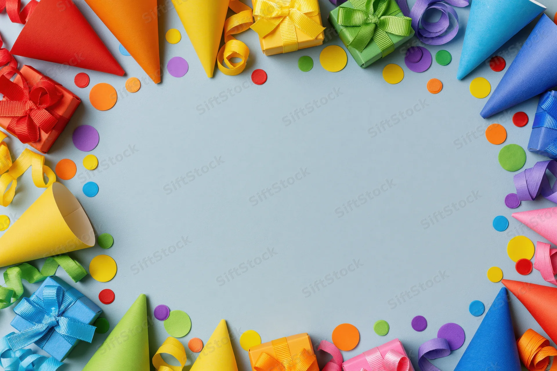 Rainbow party supplies arranged in a circular frame on blue background with copyspace in center