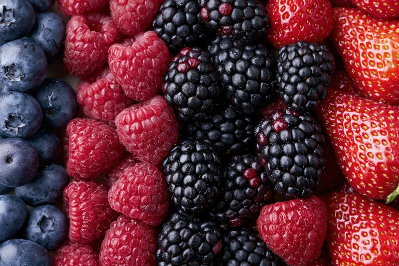Four varieties of fresh berries arranged in vertical stripes