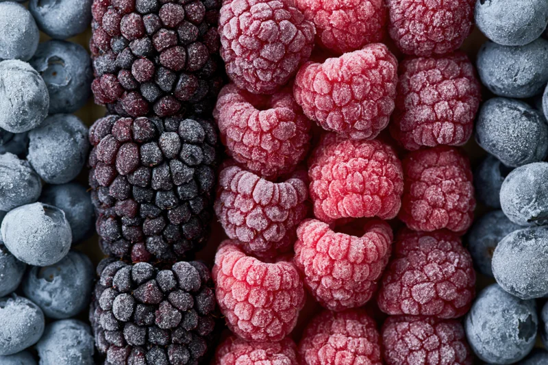 Frozen mixed berries arranged in vertical rows of raspberries, blackberries and blueberries filling the frame