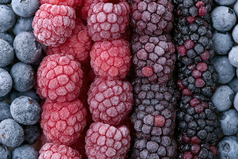 Frozen mixed berries arranged in vertical rows of raspberries, blueberries and blackberries filling the frame