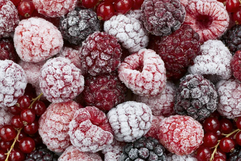 Closeup of frozen mixed berries including raspberries, blackberries and redcurrants covered in frost