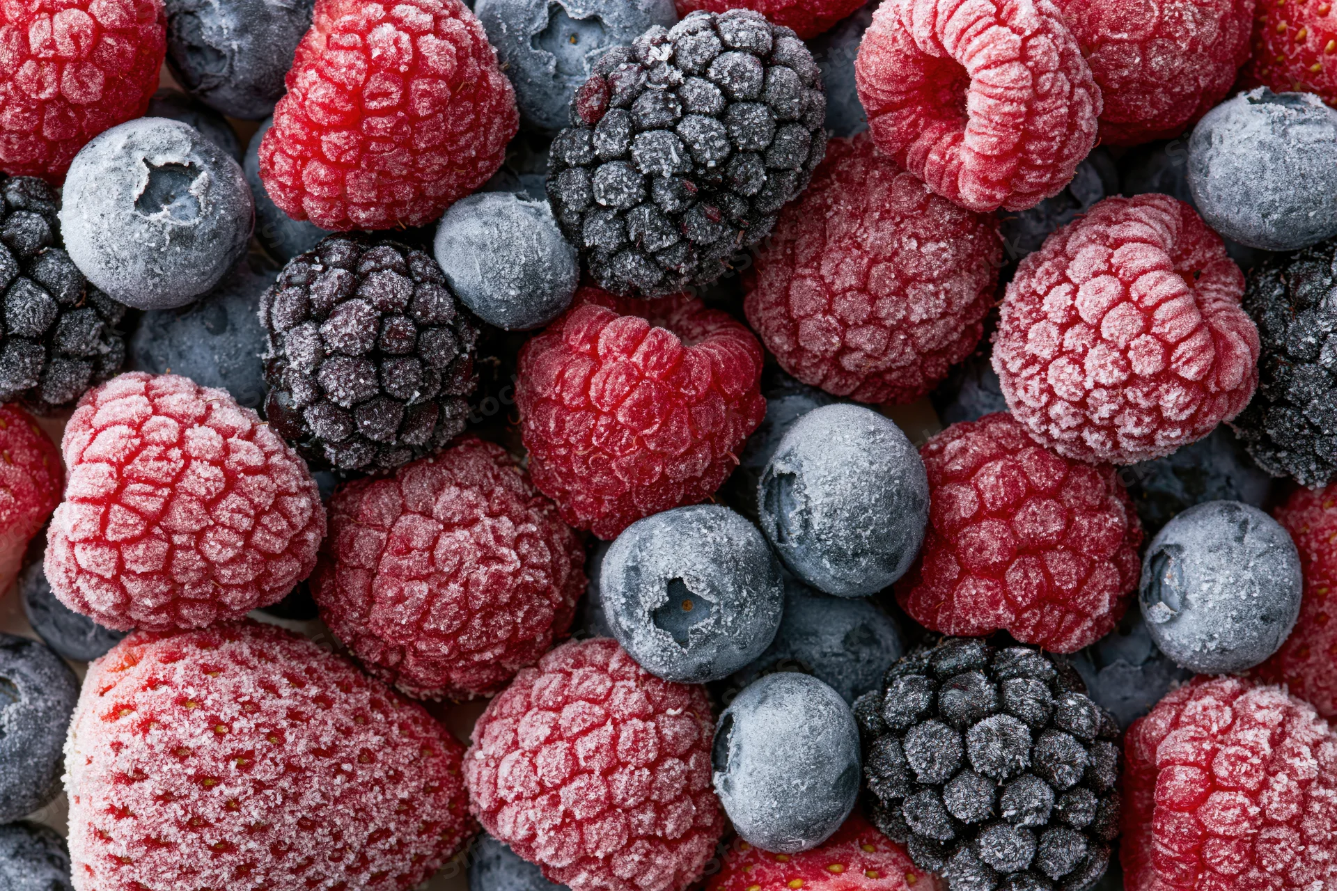 Closeup of frozen mixed berries including raspberries blueberries blackberries and strawberries covered in frost
