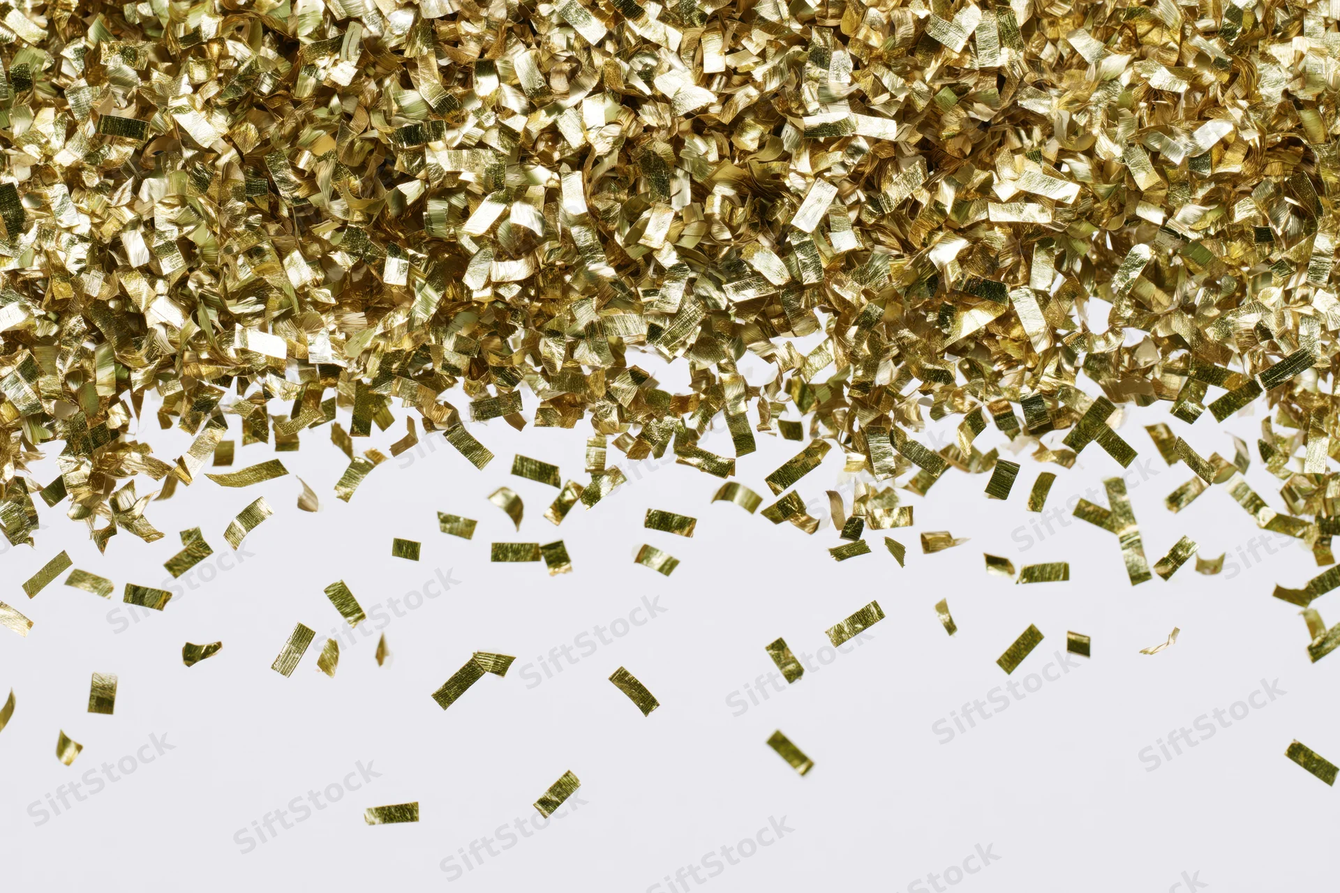 Gold metallic confetti pieces falling and scattering mid-air against white background
