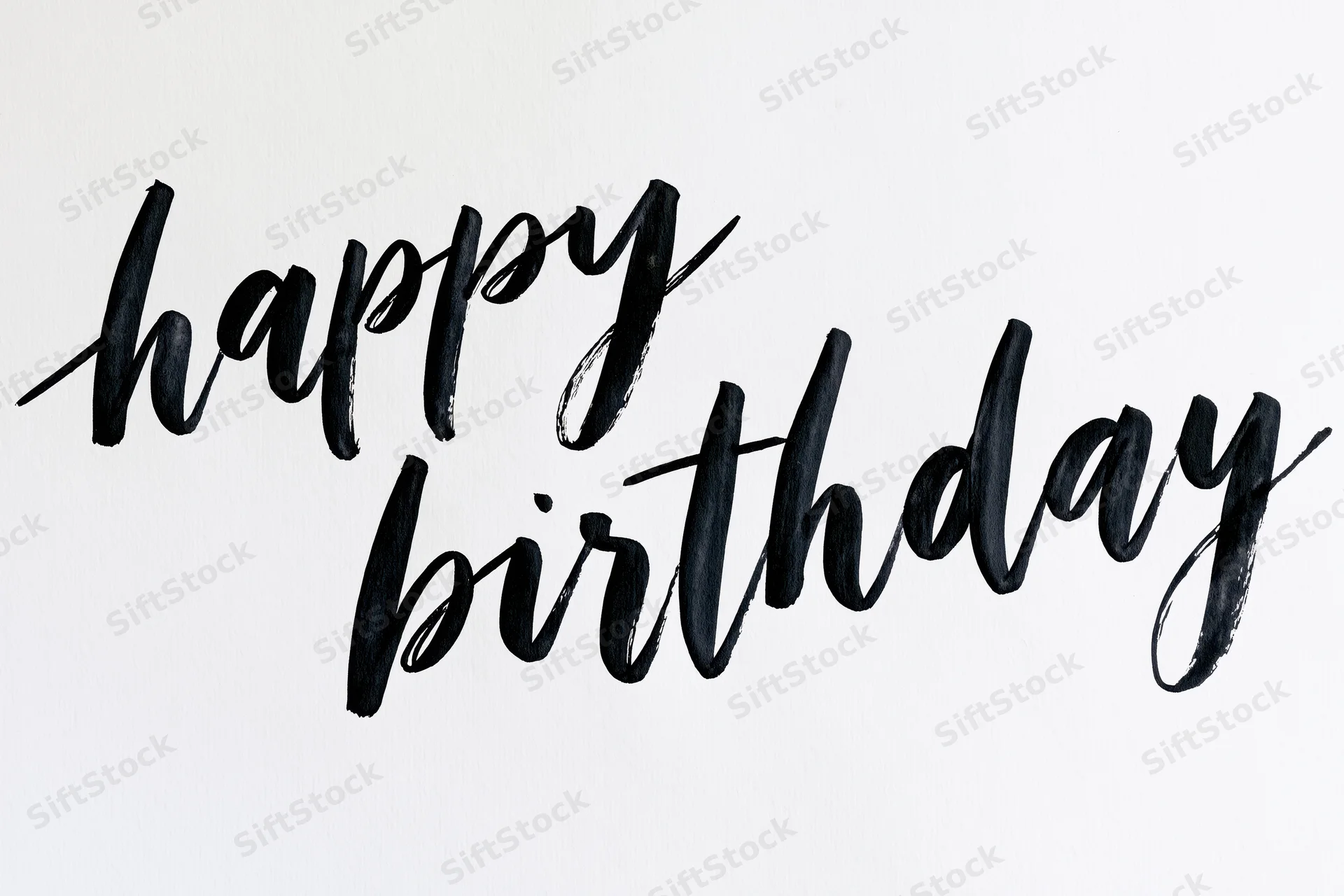 Hand-lettered happy birthday text in black brush calligraphy on white background
