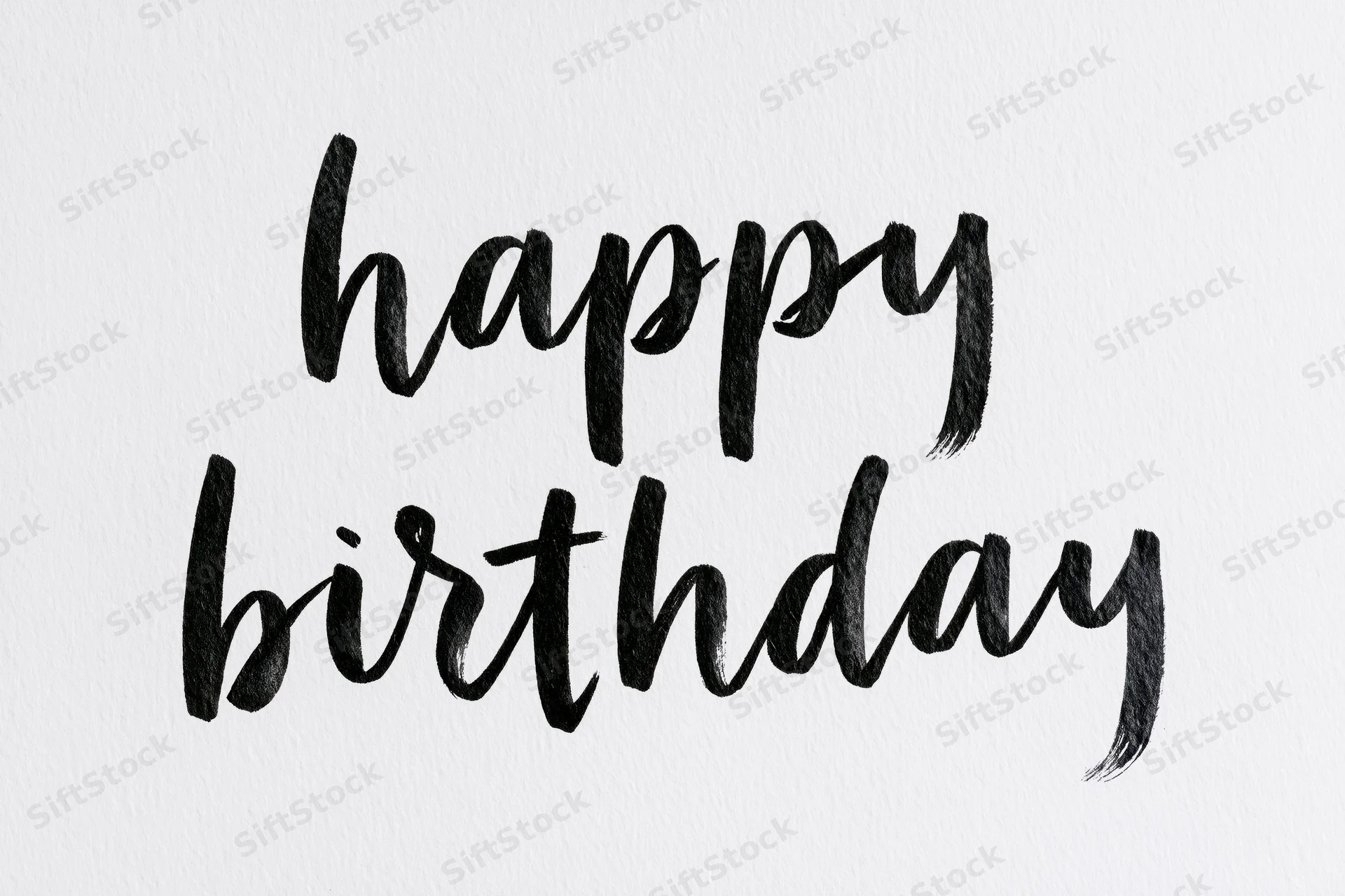 Hand-lettered happy birthday brush calligraphy on textured white paper