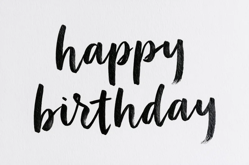Hand-lettered happy birthday brush calligraphy on textured white paper