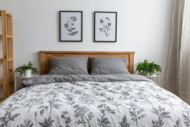 Double bed with wooden headboard and floral bedding in minimalist scandinavian bedroom