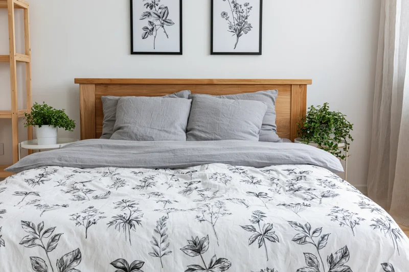 Double bed with gray bedding and botanical pattern in minimalist scandinavian bedroom