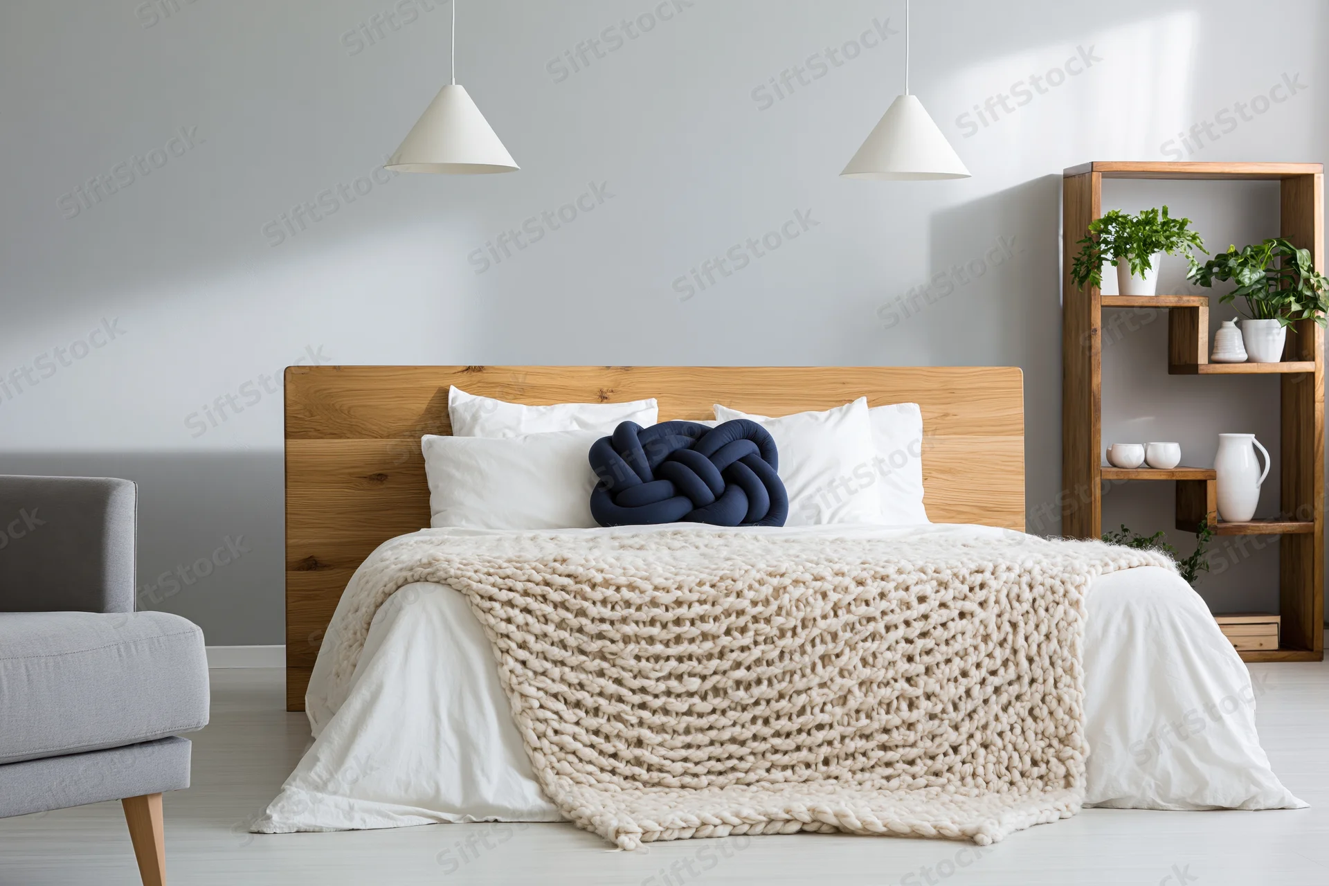 Minimalist scandinavian bedroom with wooden bed and knit blanket, white bedding, pendant lights, and open shelf with plants