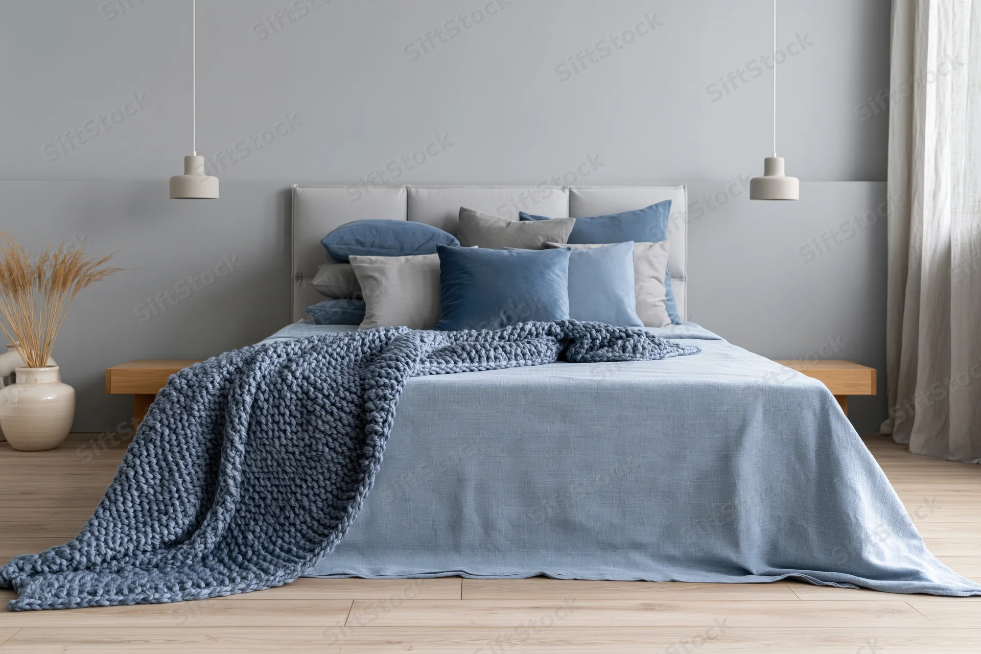 Queen bed with blue bedding and knitted blanket in minimalist scandinavian bedroom