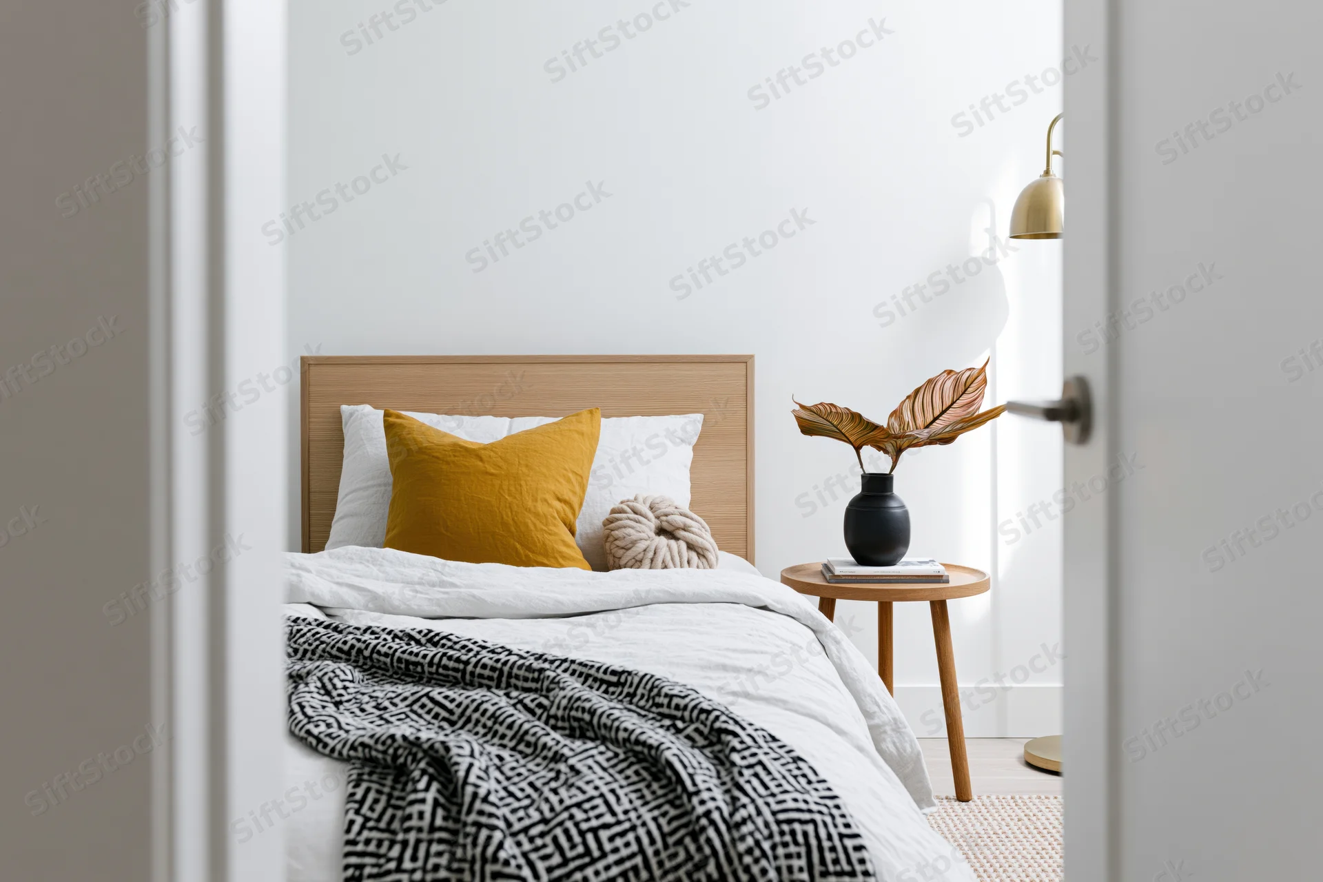 View through doorway into minimalist bedroom with single bed and wooden side table