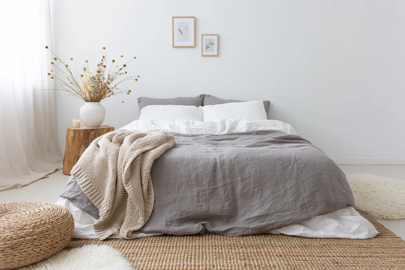 Minimalist bedroom interior with a made double bed layered in textiles