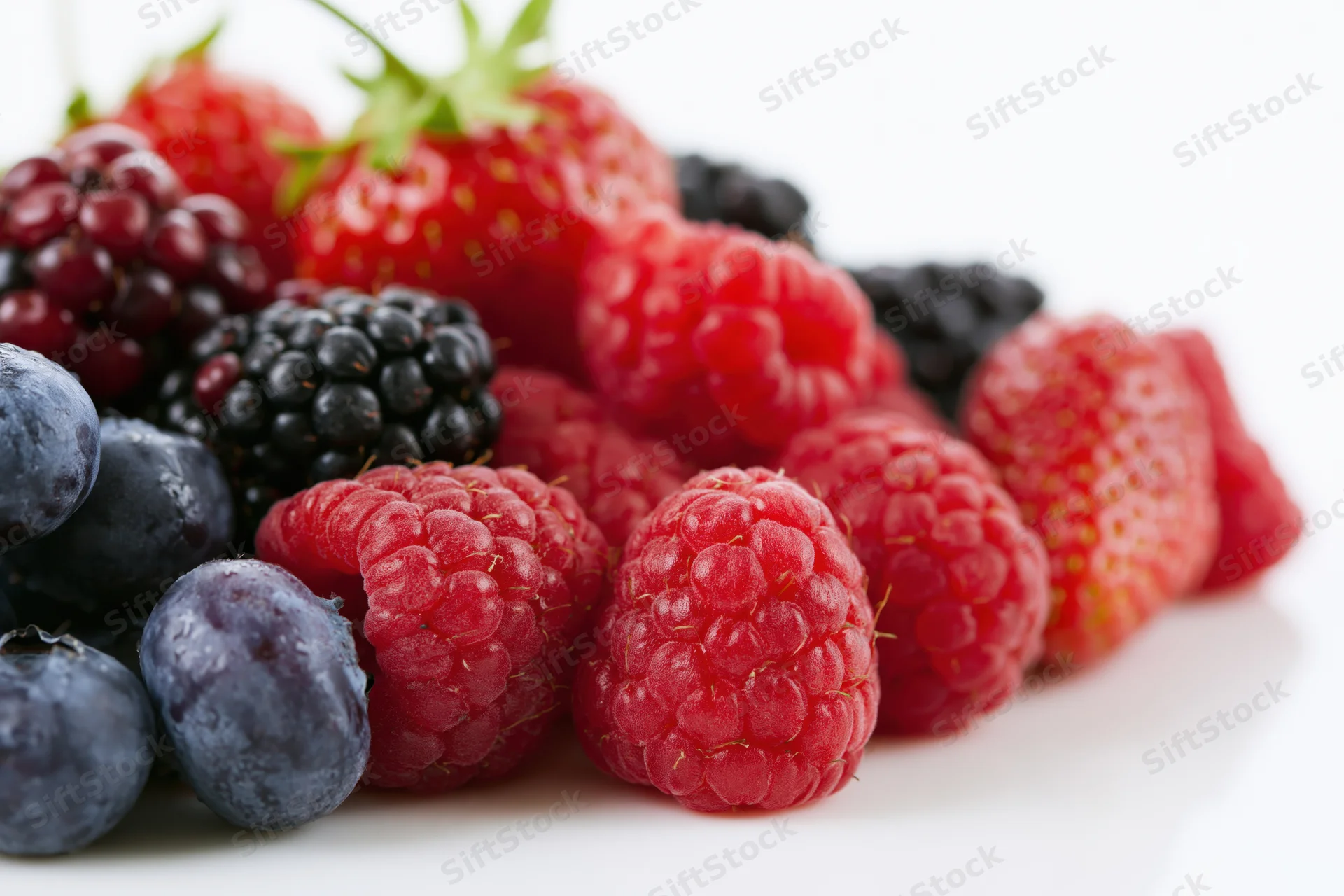 Mixed fresh berries piled together on a white surface