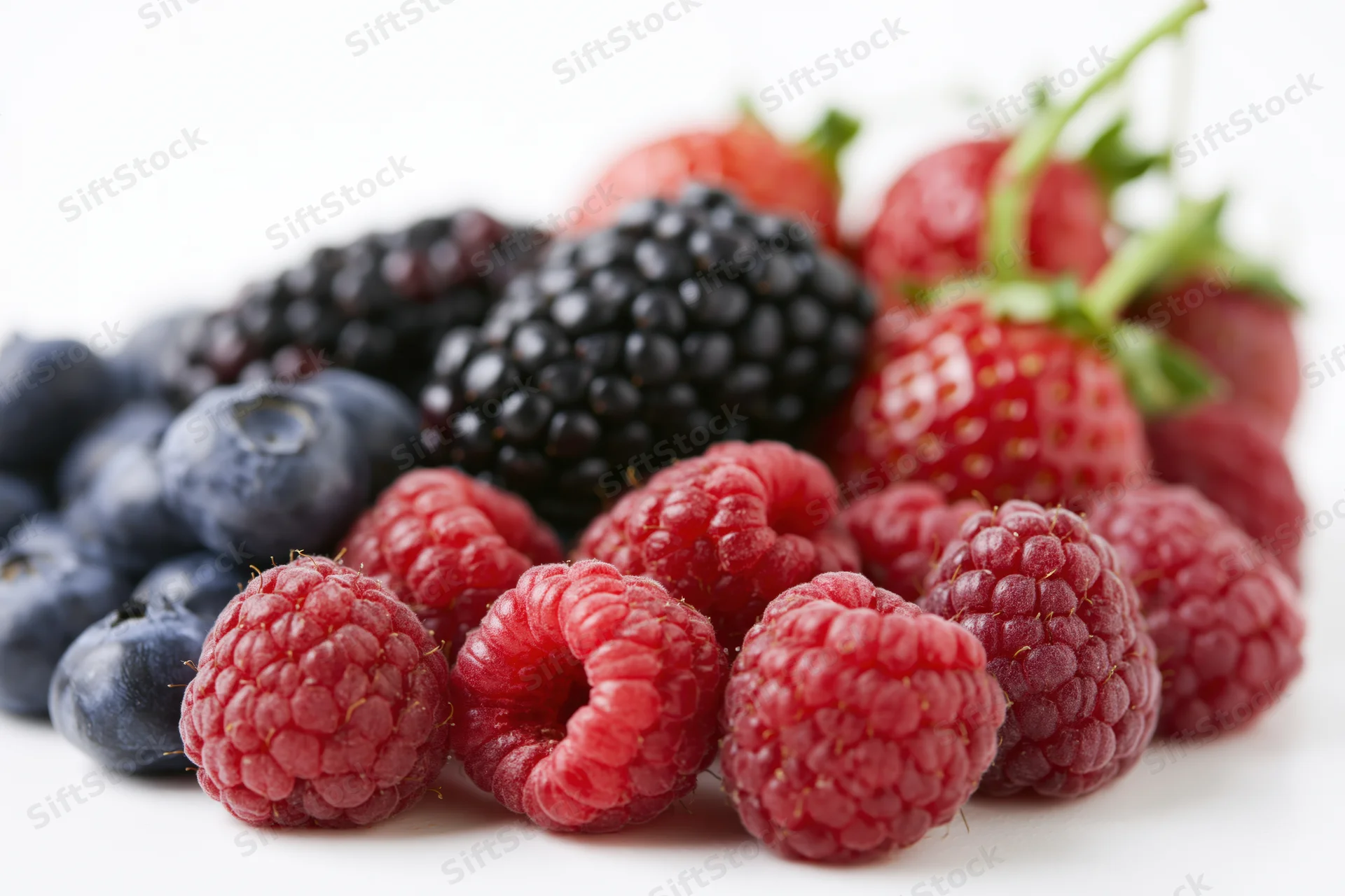 Mixed fresh berries piled together on a white surface