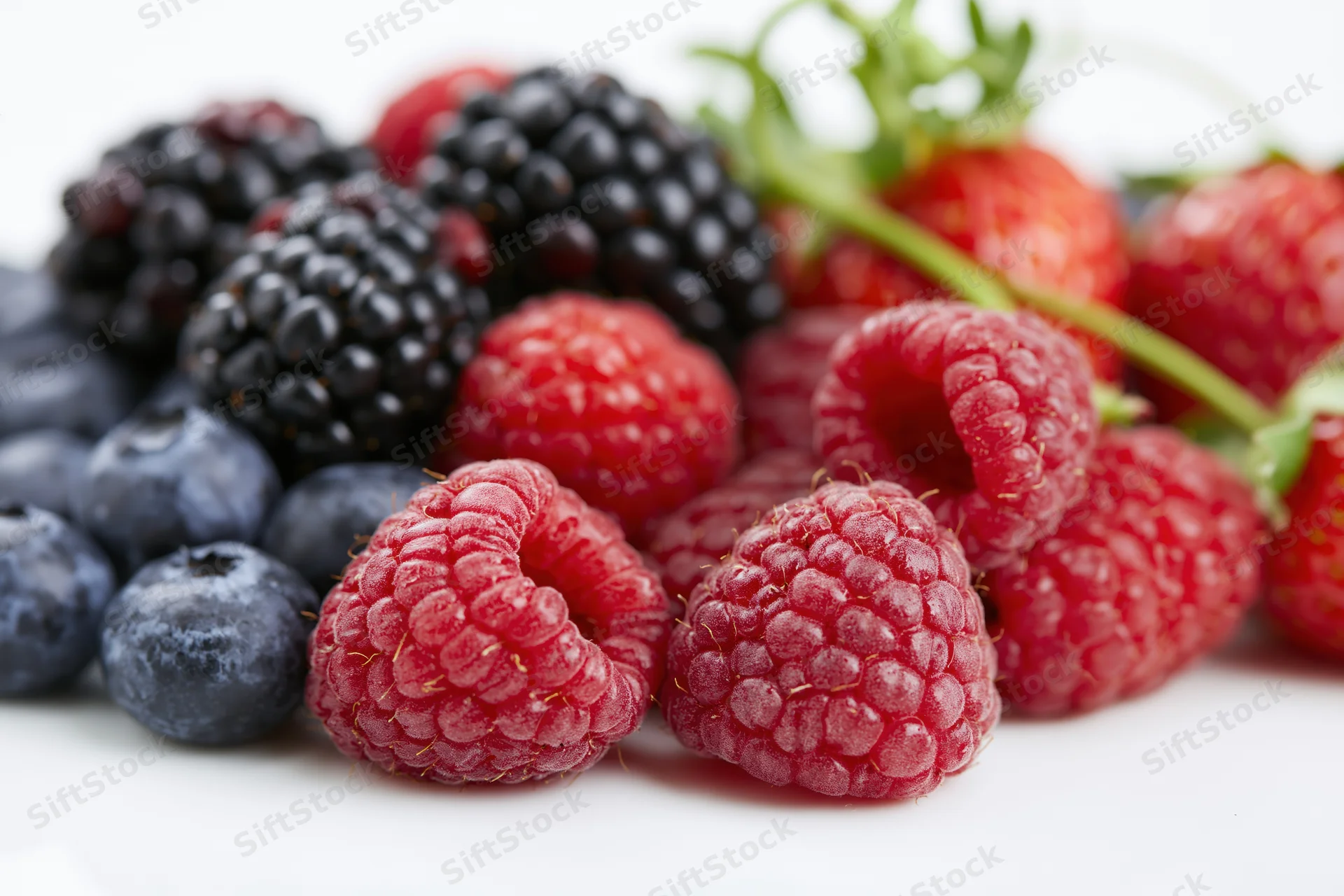 Mixed fresh berries piled together on a white surface