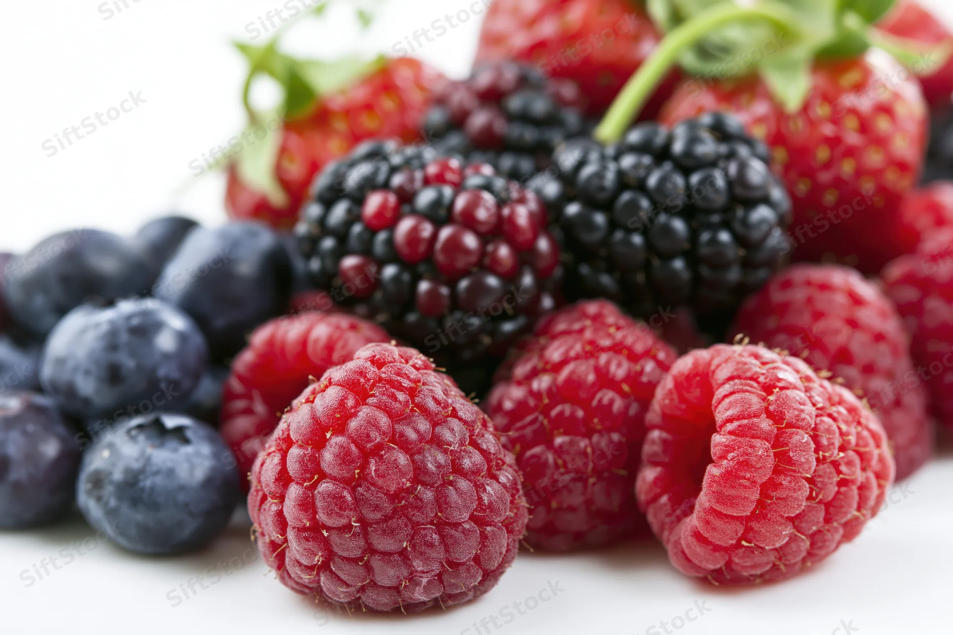 Mixed fresh berries arranged in a loose pile on a white surface