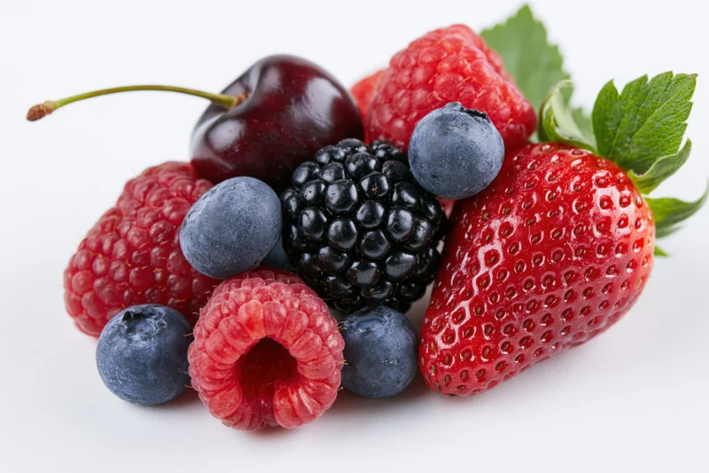 Mixed fresh berries arranged in a cluster on white background