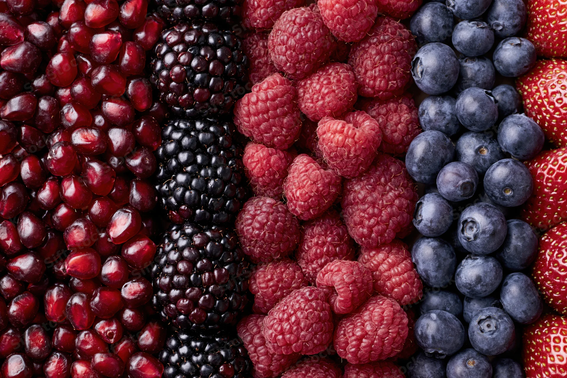 Vertical columns of mixed fresh berries arranged in a full frame closeup