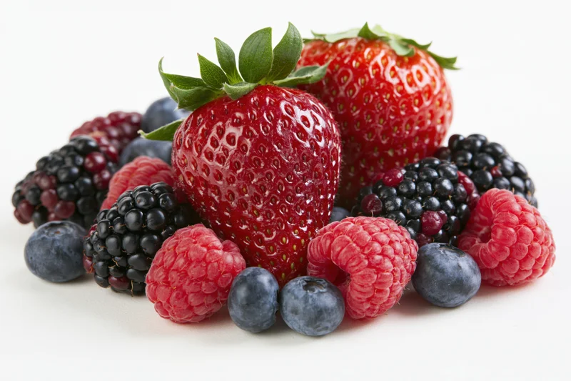 Mixed fresh berries arranged in a cluster on a white surface