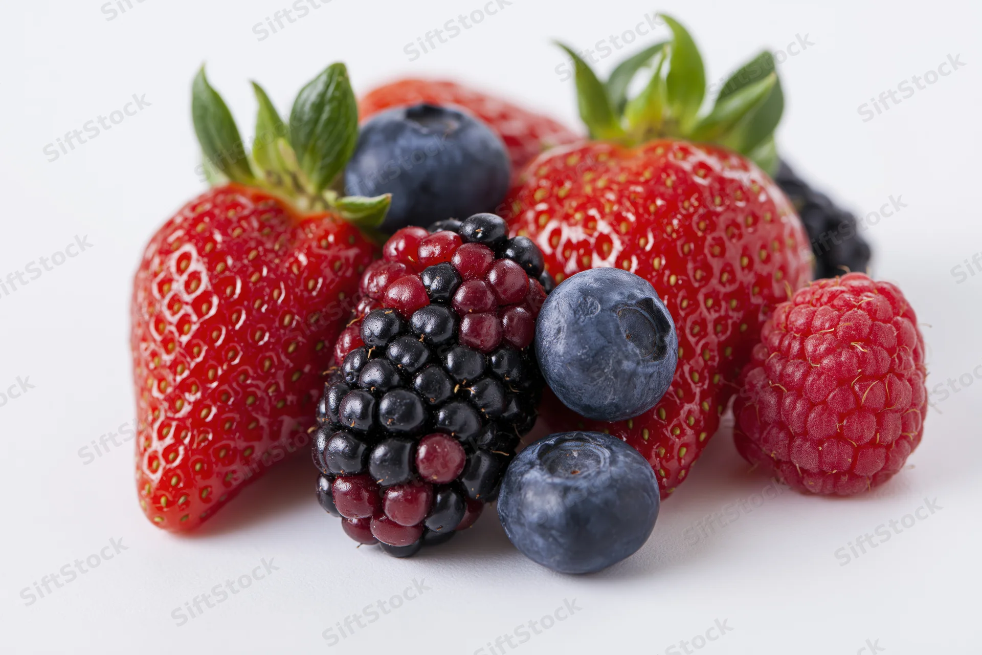 Mixed fresh berries arranged in a cluster on a white surface
