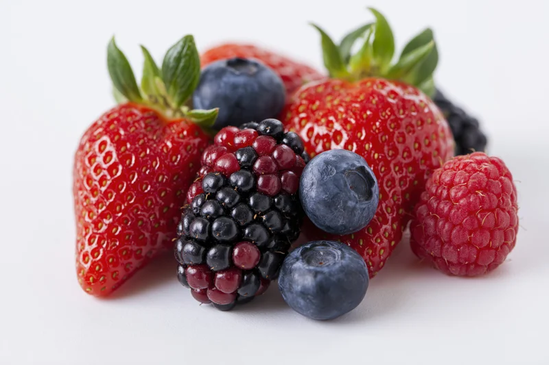 Mixed fresh berries arranged in a cluster on a white surface