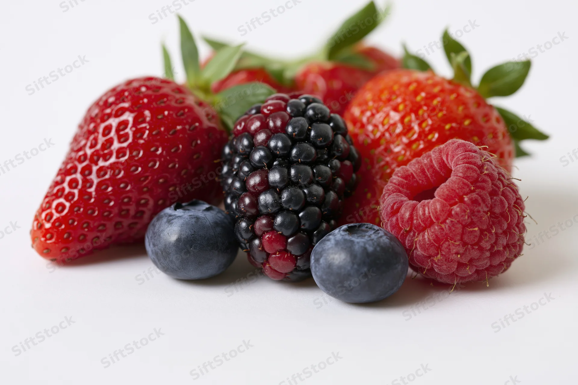 Mixed fresh berries arranged in a cluster on a white surface