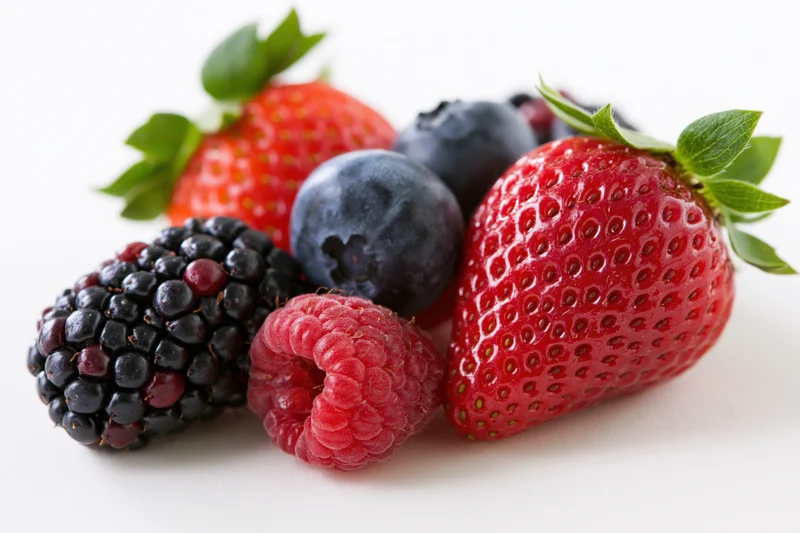 Mixed fresh berries arranged on a white surface