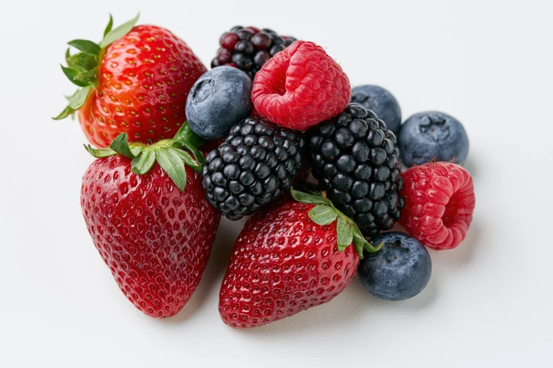 Mixed fresh berries including strawberries blueberries raspberries and blackberries arranged on white background