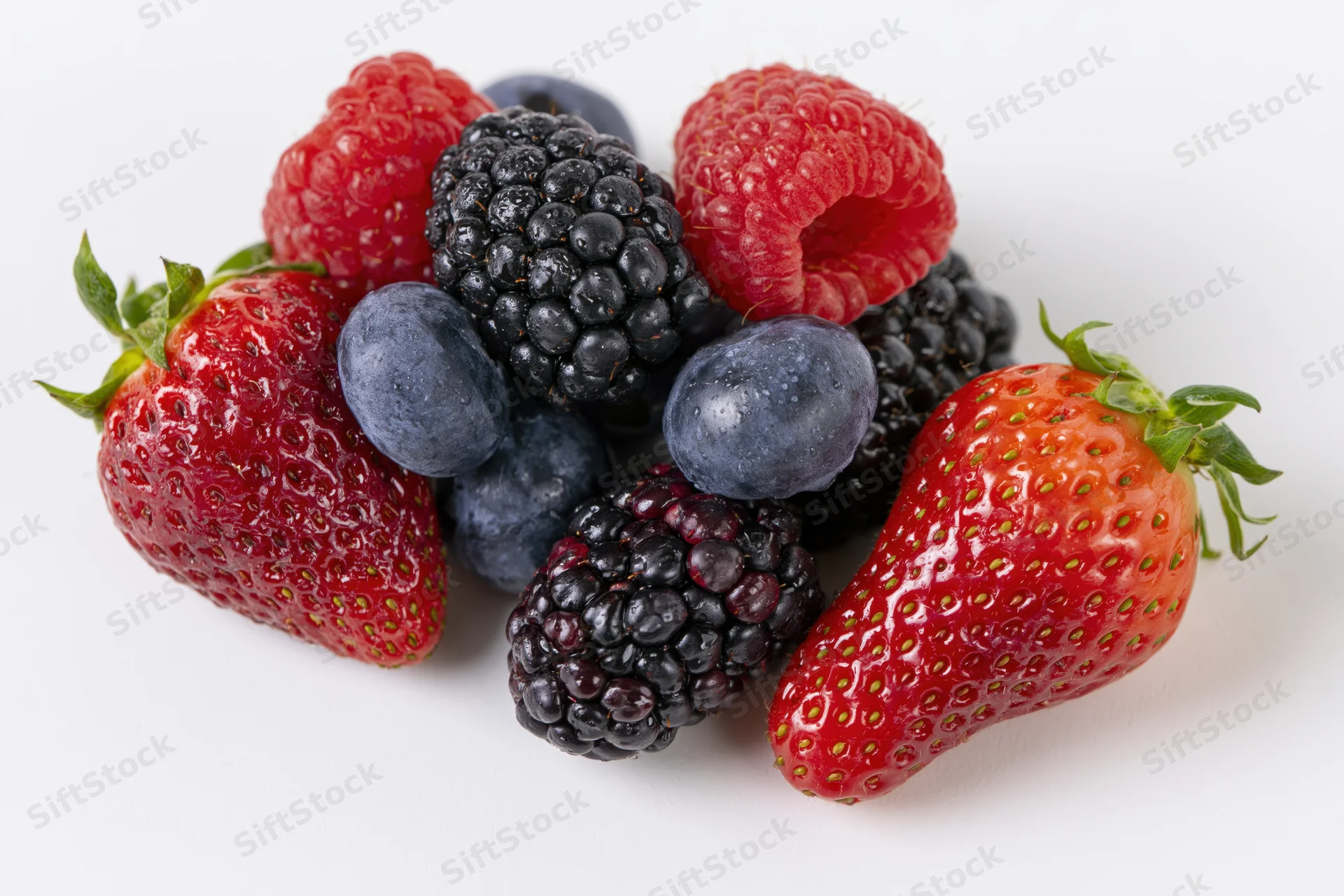 Mixed fresh berries including strawberries raspberries blackberries and blueberries arranged on white background