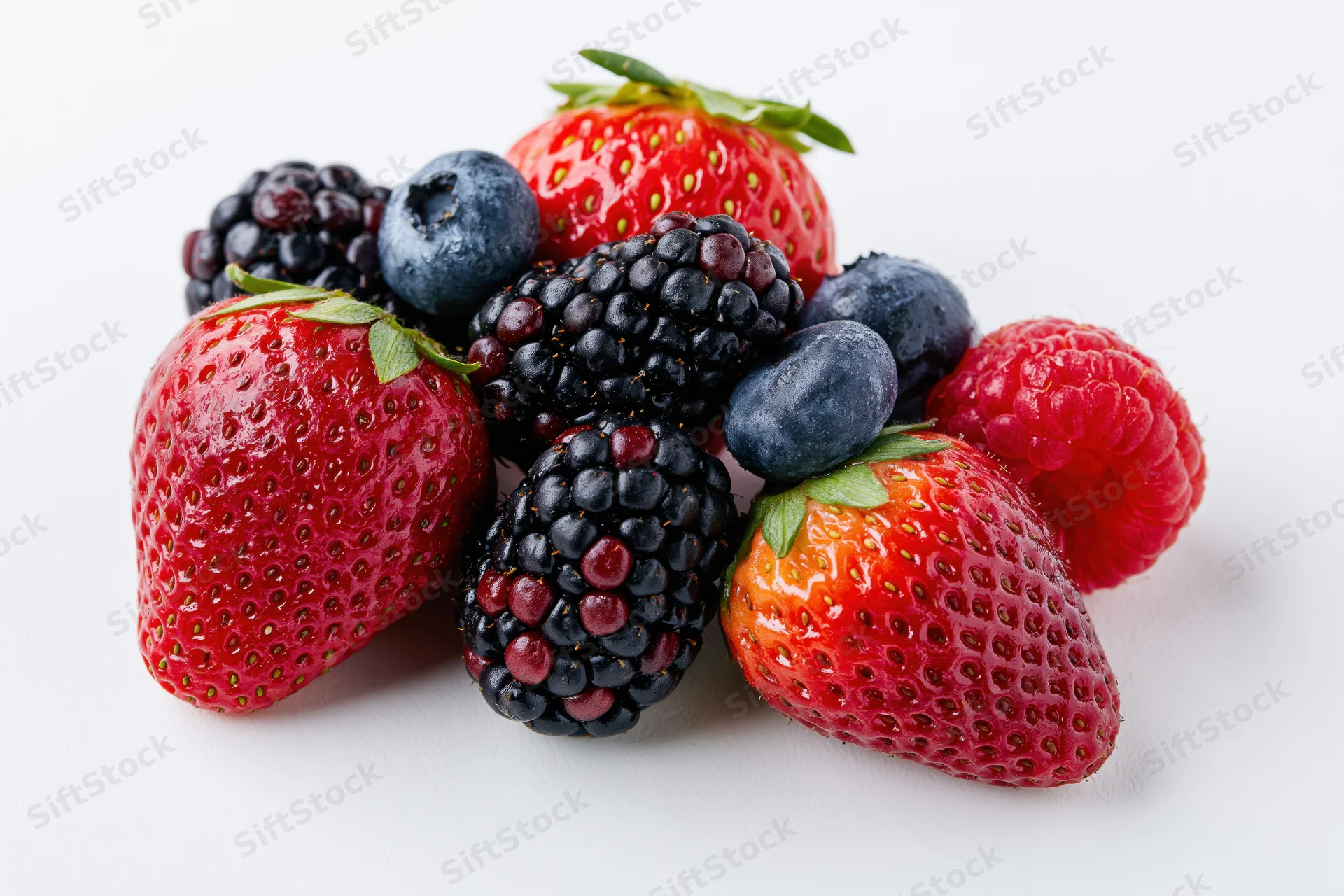 Mixed fresh berries including strawberries blueberries blackberries and raspberries arranged on white background