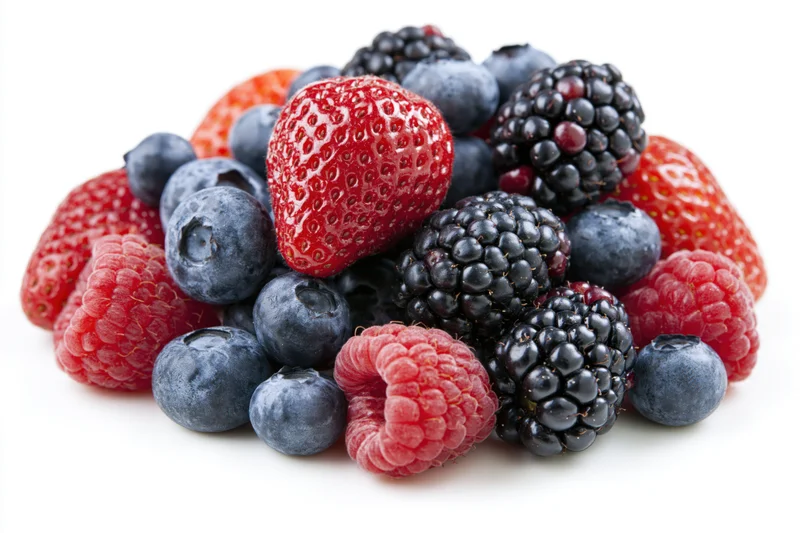Mixed fresh berries piled together on white background